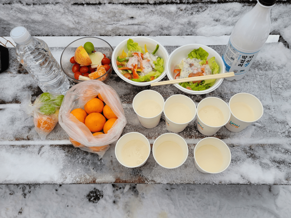 겨울 산행광교산 정상에서 연어회 샐러드와 과일, 야채, 막걸리 한잔 사진이다. 촬영일 2023.01.01.